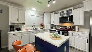Een moderne keuken met witte kasten, een centraal eiland en oranje stoelen.