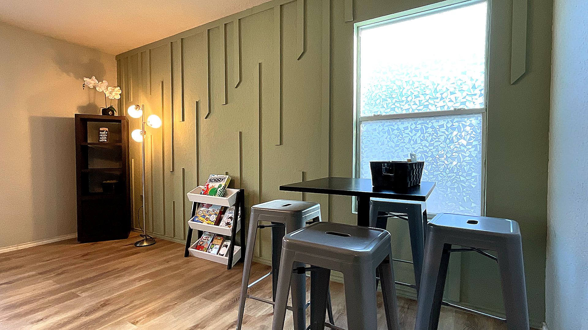 A room with a wooden floor, a desk with a chair, a bookshelf, and a window with a view.
