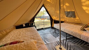 Een tent met twee bedden, elk met een bedovertrek en kussens met een patroon.