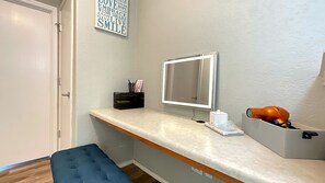 Ein Badezimmer mit Waschtisch, Spiegel, einer blauen Bank und einer Wand mit motivierenden Sprüchen.