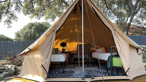 Een tent met twee bedden, een tafeltje en een stoel.