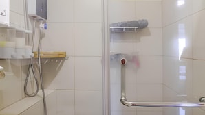 Et bruseområde med glasdør, håndbruser og gelænder.
