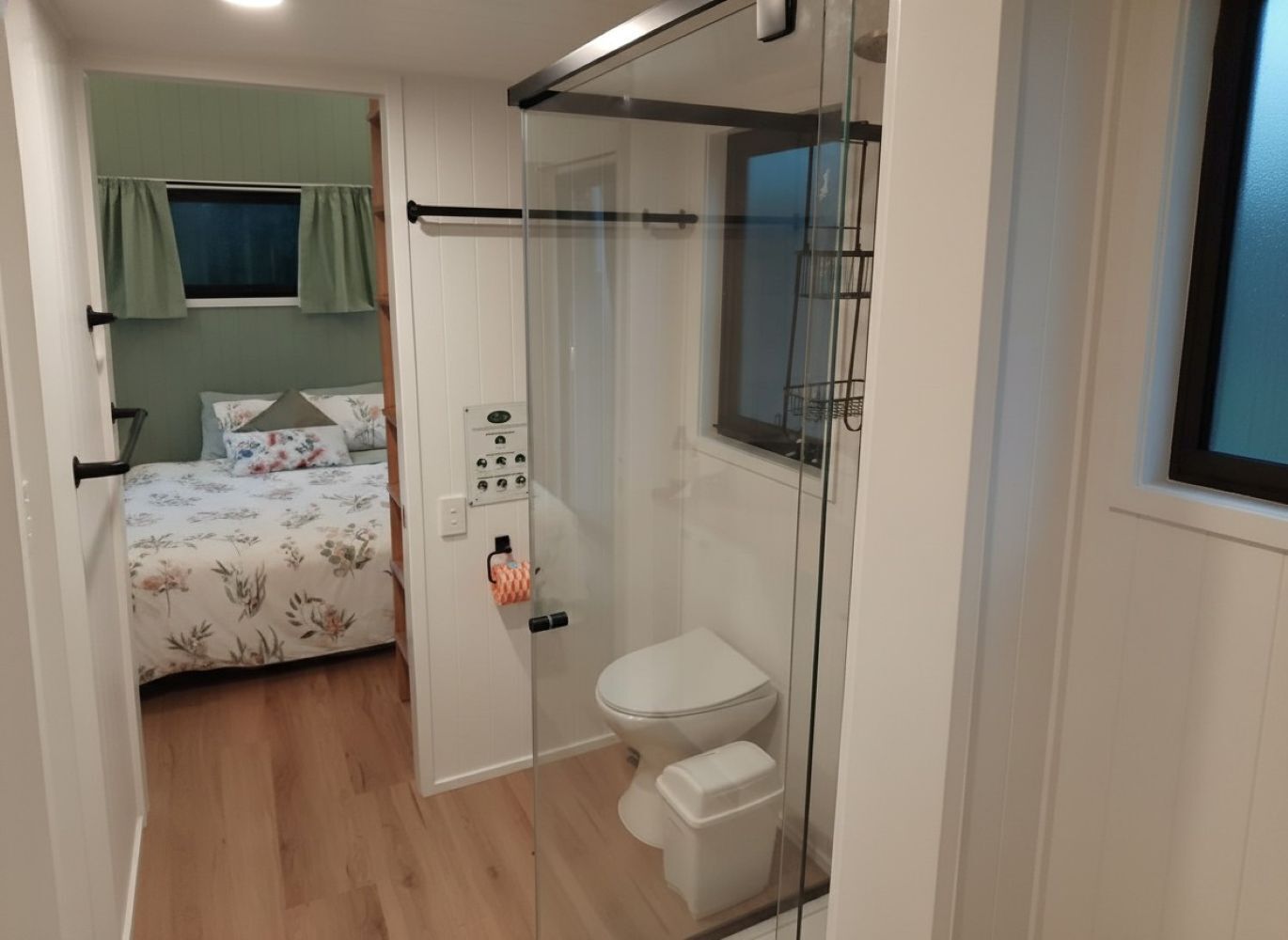A compact bedroom with a bed, a bedside table, and a window with curtains.