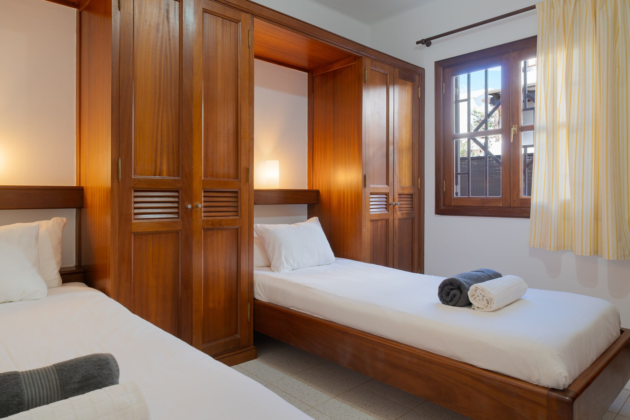 A hotel room with a wooden bed, a wardrobe, and a window with curtains.