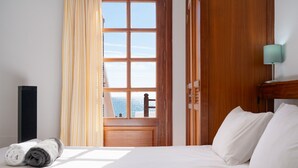 Habitación de hotel con cama, ventana con cortinas, lámpara y vista al exterior.