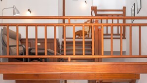 Amplia sala de estar con techo alto, escalera de madera, sofá, mesa de comedor y televisor.
