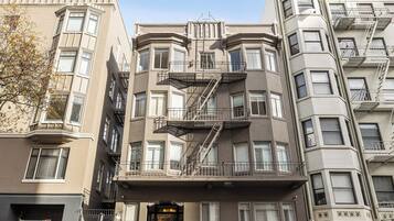 A multi-story building with bay windows, fire escapes, and a garage entrance.