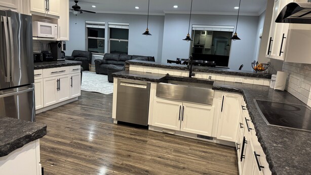 A modern kitchen with white cabinets, stainless steel appliances, and a central island with a sink. - Peaceful 4-bedroom house near lake access with room for multiple boats. (Moses Lake)