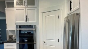 A kitchen with white cabinetry, a stainless steel refrigerator, and an oven. - Peaceful 4-bedroom house near lake access with room for multiple boats. (Moses Lake)