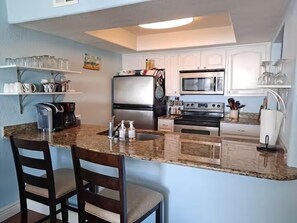 A kitchen with a granite countertop, stainless steel appliances, and white cabinetry. - Beachfront Water View in Perfect Paradise at Bayfront Kontiki! (Rockport)