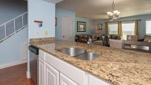 A kitchen with granite countertops, white cabinetry, and a double sink. - Beachfront Water View in Perfect Paradise at Bayfront Kontiki! (Rockport)