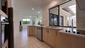 Uma cozinha moderna com máquina de lavar louça, forno e uma grande janela com vista para um jardim.