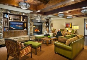 A cozy living room with a stone fireplace, a television, and comfortable seating. - Ski In and Ski Out at Hyatt Northstar Lodge in Luxury Studio Romantic Ski Escape (Truckee)