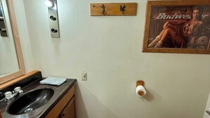 Un baño con tocador de madera, lavamanos, inodoro y zona de ducha.