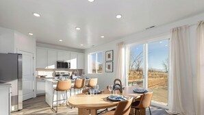 Una cocina moderna con armarios blancos, una isla central y una zona de comedor con una mesa redonda y sillas.