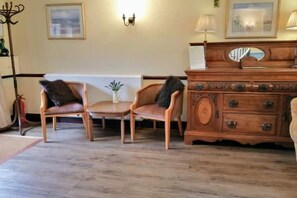 A room with two wooden chairs, a small table, a wooden dresser with drawers, and a mirror. - Cottage 2 – Three bedroom cottage (Salisbury)