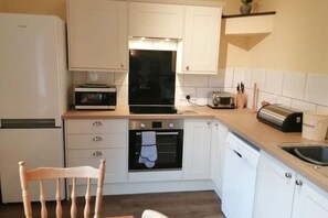 A compact kitchen with white cabinets, a built-in oven, a toaster, and a sink. - Cottage 2 – Three bedroom cottage (Salisbury)