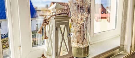 A window sill with a white lantern and a vase of dried plants.
