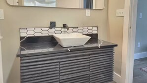 A bathroom with a white vessel sink, black countertop, and a hexagonal tile backsplash. - 4 miles to Mercedes Benz Stadium-Sleeps 4-Best Value ATL STAY (Atlanta)