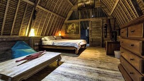 Ein rustikaler Raum mit schräge Decke, Holzmöbeln und einem Bett mit weißer Bettdecke.