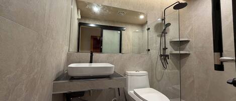 A modern bathroom with a white sink, toilet, and a glass-enclosed shower area.