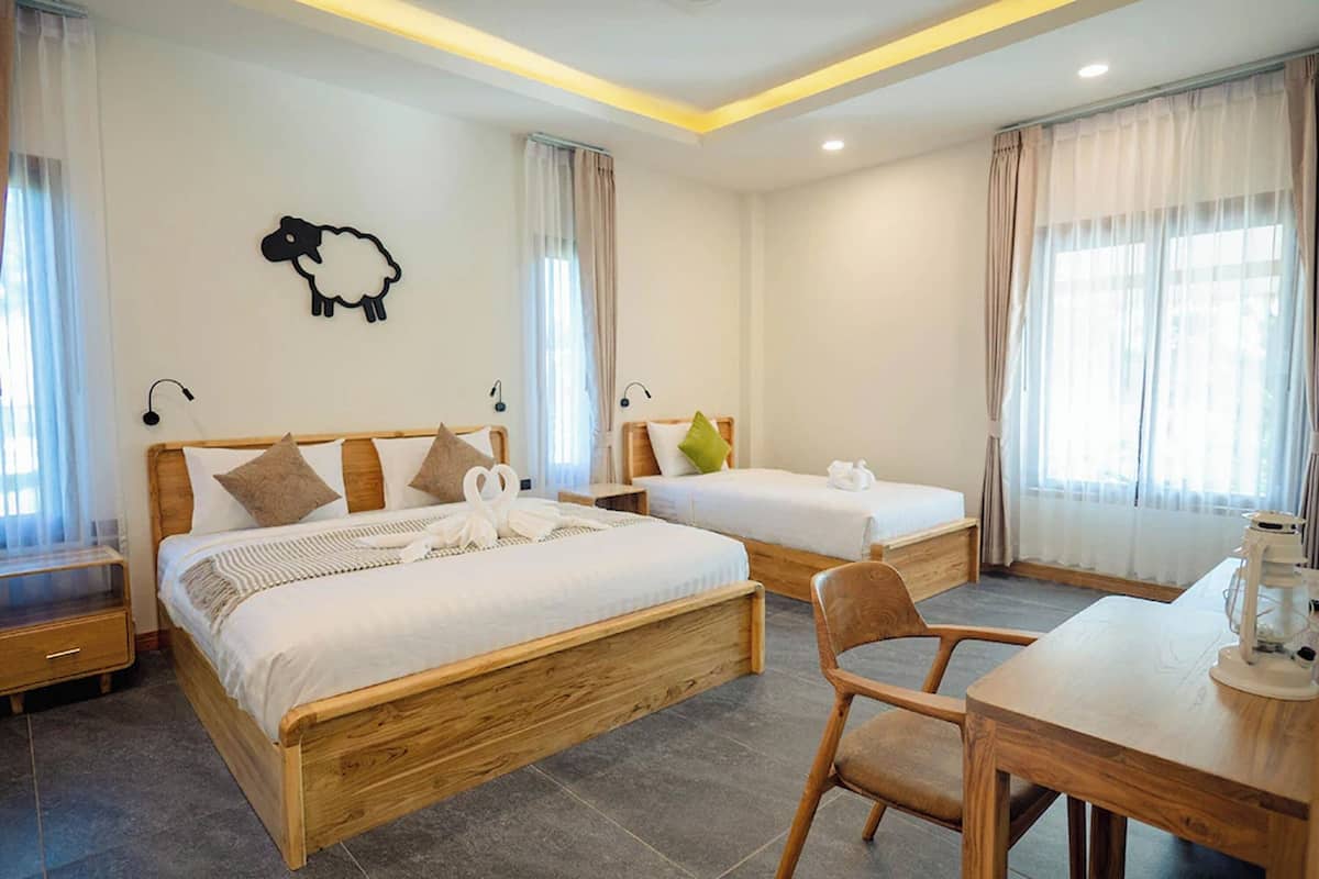 Una habitación de hotel con dos camas, un escritorio de madera y una lámpara.