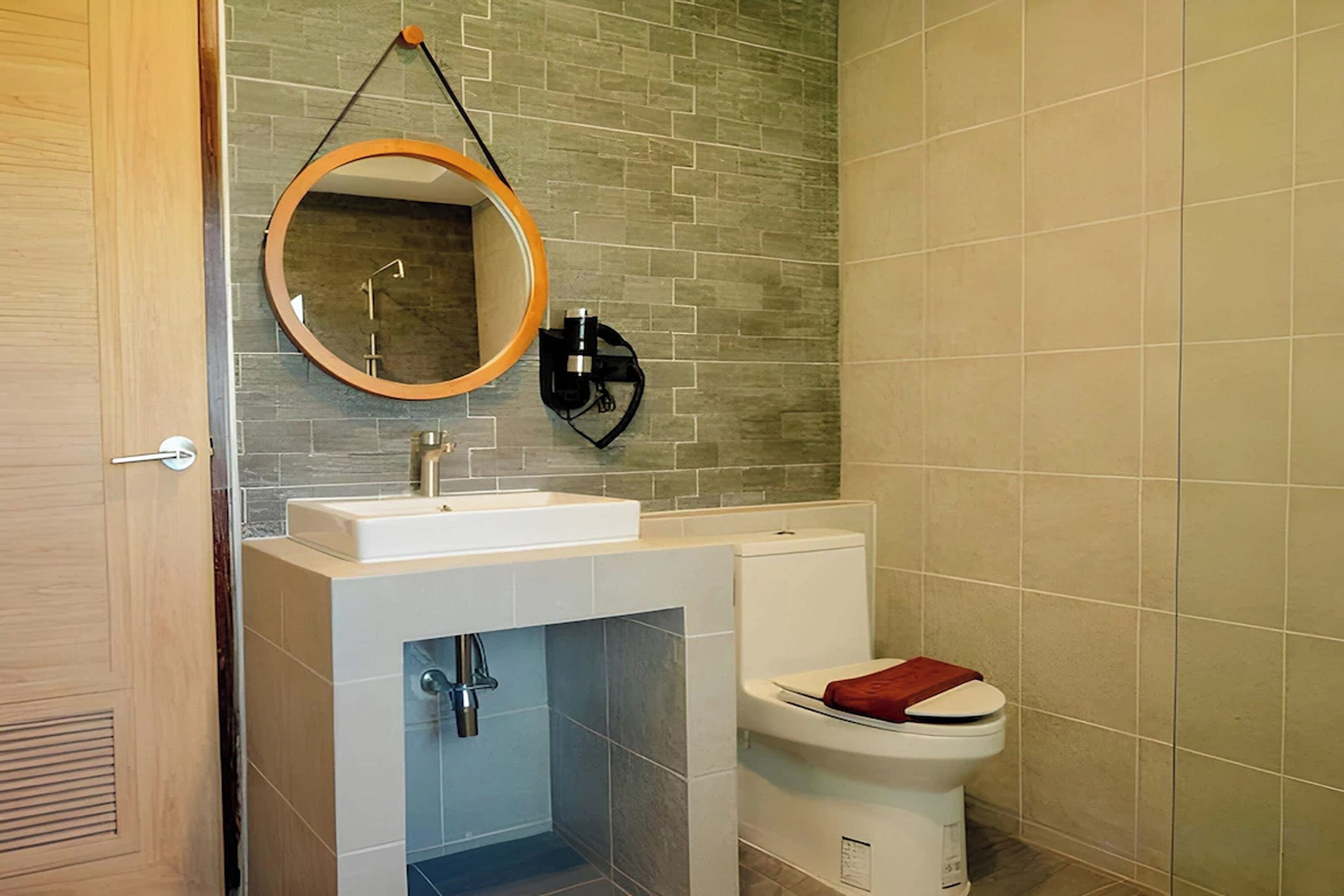 A bathroom with a white sink, a toilet, and a mirror with a wooden frame.