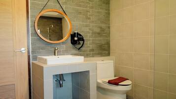 A bathroom with a white sink, a toilet, and a mirror with a wooden frame.