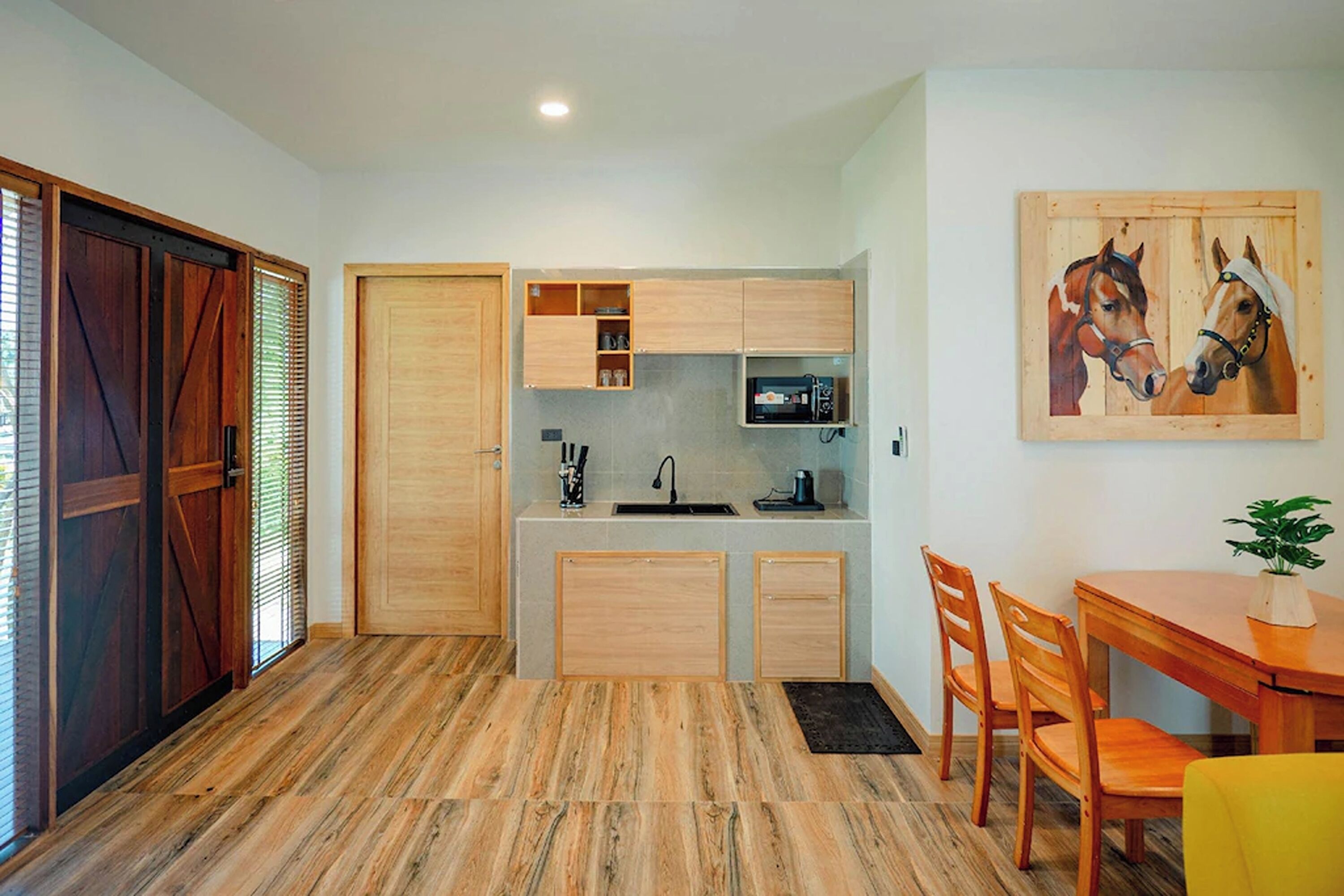 A compact kitchen with wooden cabinets, a sink, and a dining area with chairs and a table.
