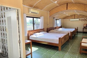 A hotel room with three wooden beds, a tiled floor, and a curved ceiling.