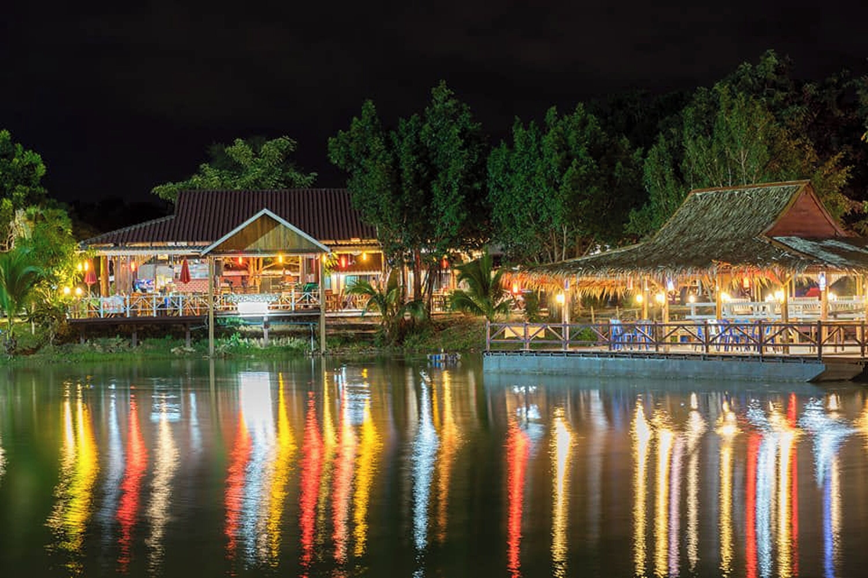 Un hotel frente al agua, con el reflejo de luces de colores sobre el agua.
