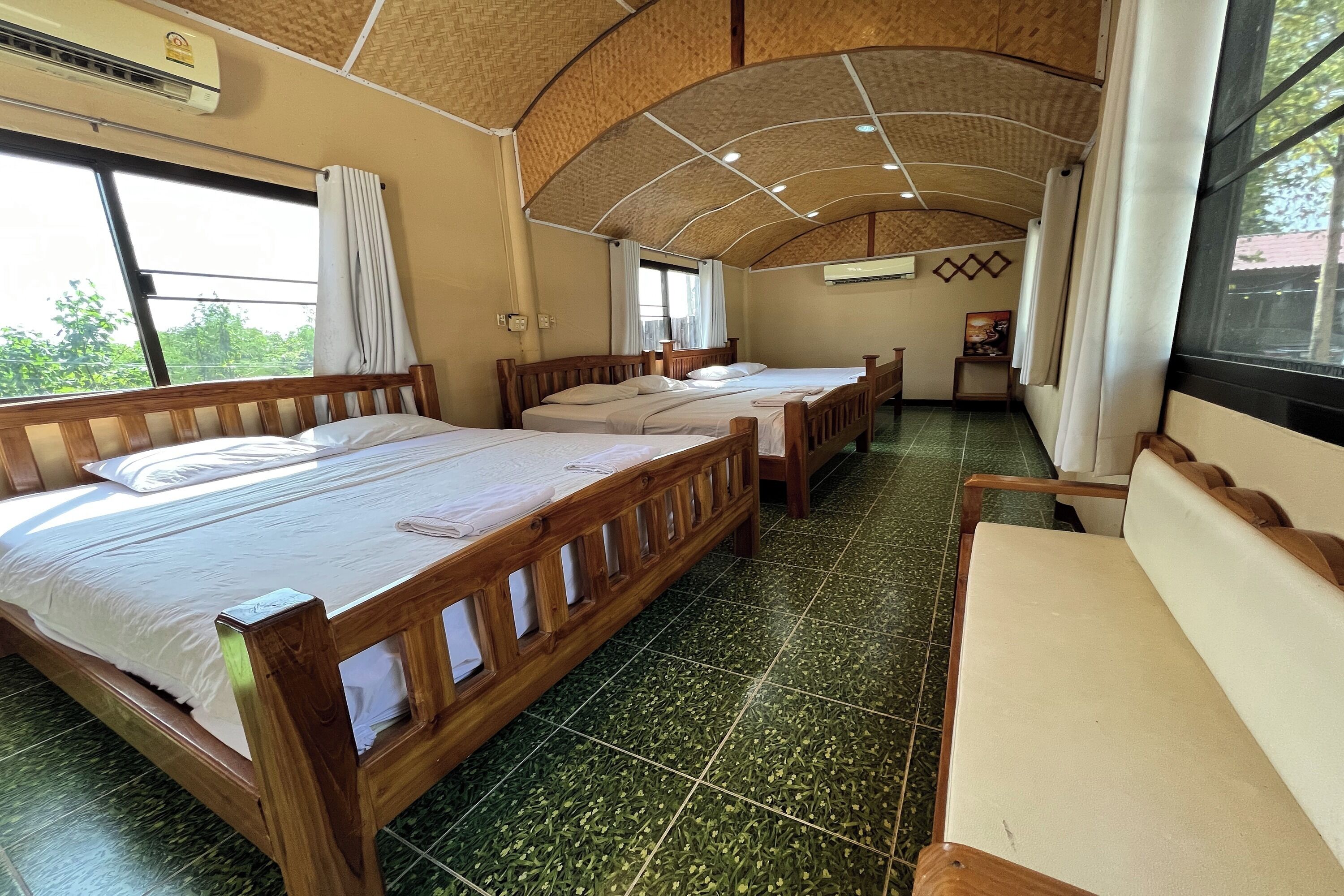 A room with two wooden beds, a bench, and a large window.