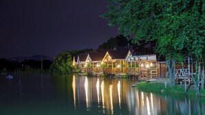 A lakeside wooden structure with multiple rooms, a dock, and a reflection in the water. - Rabiangmai Resort (Kanchanaburi)