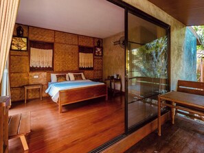 A bedroom with a wooden bed, a small bedside table, a bench, and a glass door leading to a balcony with a view of greenery. - Lion Cafe Resort (Hang Dong)