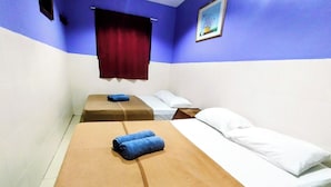 Une chambre avec deux lits, chacun recouvert d’une couverture marron et blanche, et ornée d’un rideau rouge.