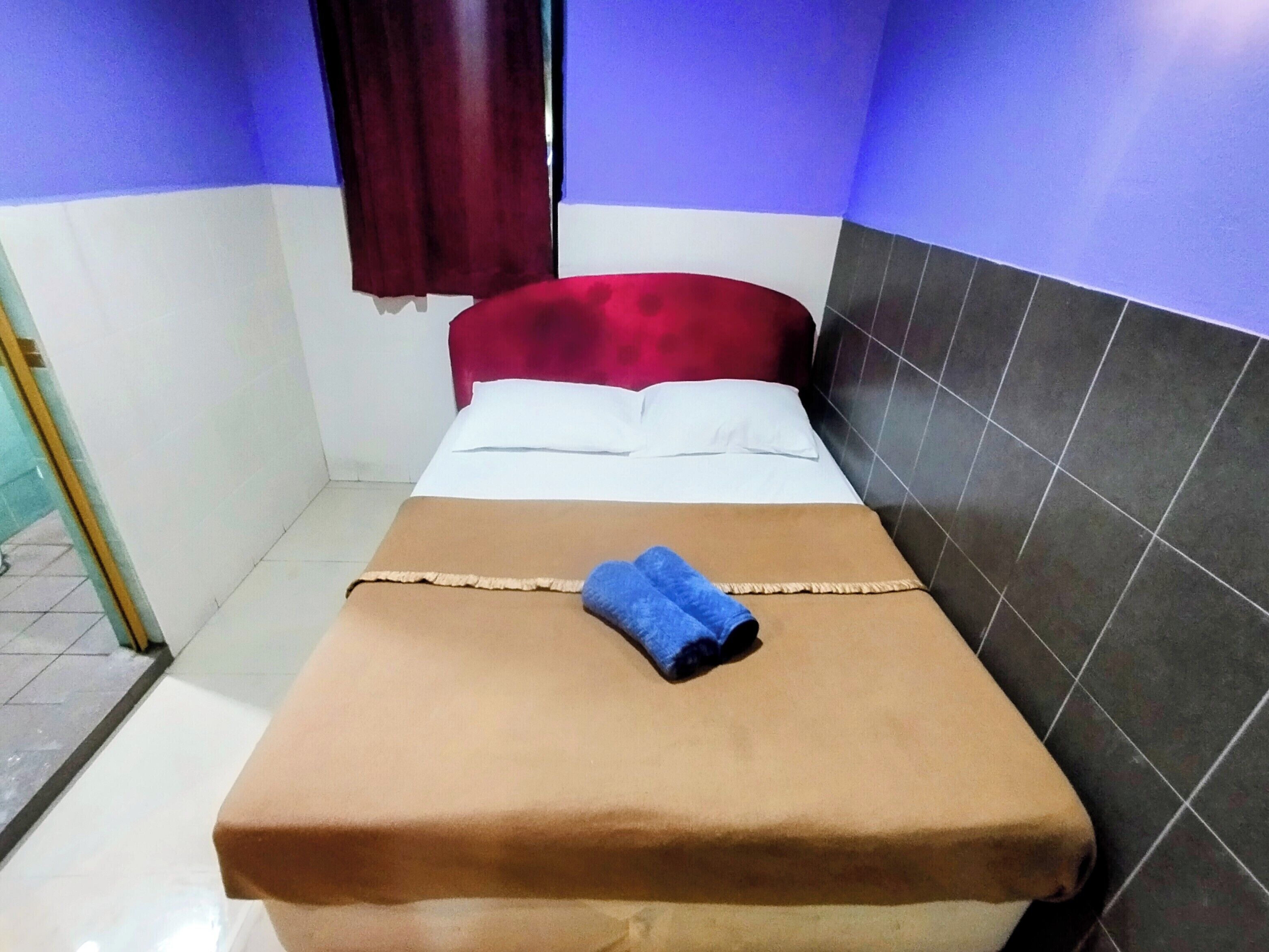 A single bed with a brown bedspread, white pillows, and a blue towel.