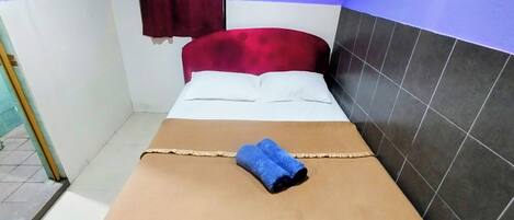 A single bed with a brown bedspread, white pillows, and a blue towel.