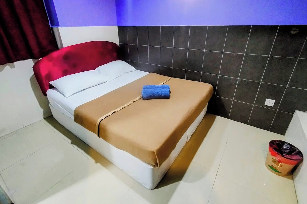 Ein Bett mit einer braunen Decke, weißen Kissen und einem blauen Handtuch.