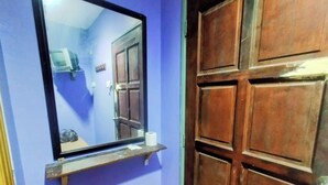 Une salle de bain avec un miroir, une porte en bois et un petit tabouret.