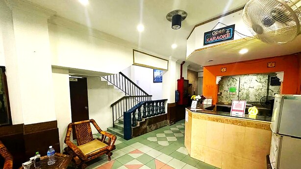 Un hall d’hôtel comprenant un comptoir d’enregistrement, un escalier et un espace détente avec des sièges.