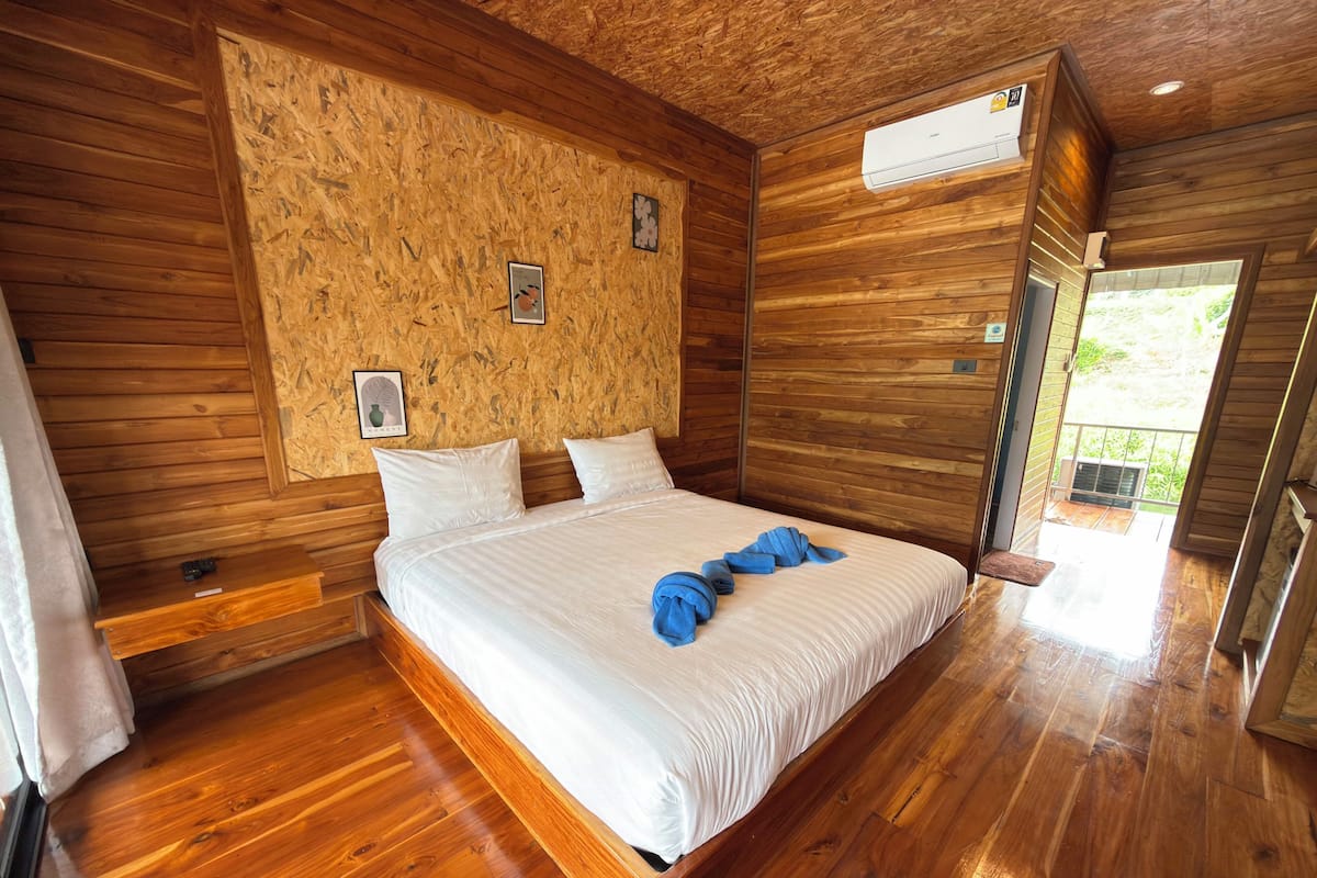 Un dormitorio con paneles de madera, una cama, almohadas y una toalla azul.