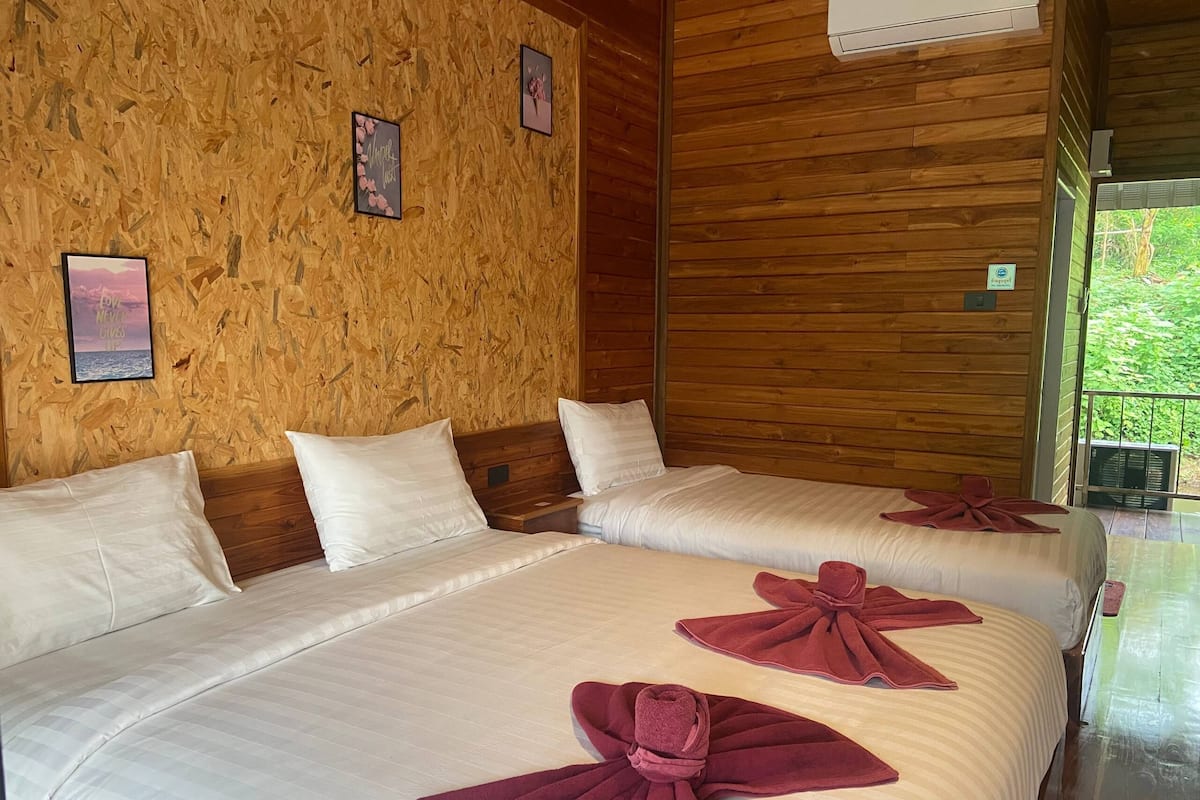 Una habitación con dos camas, paredes de madera y cuadros enmarcados.