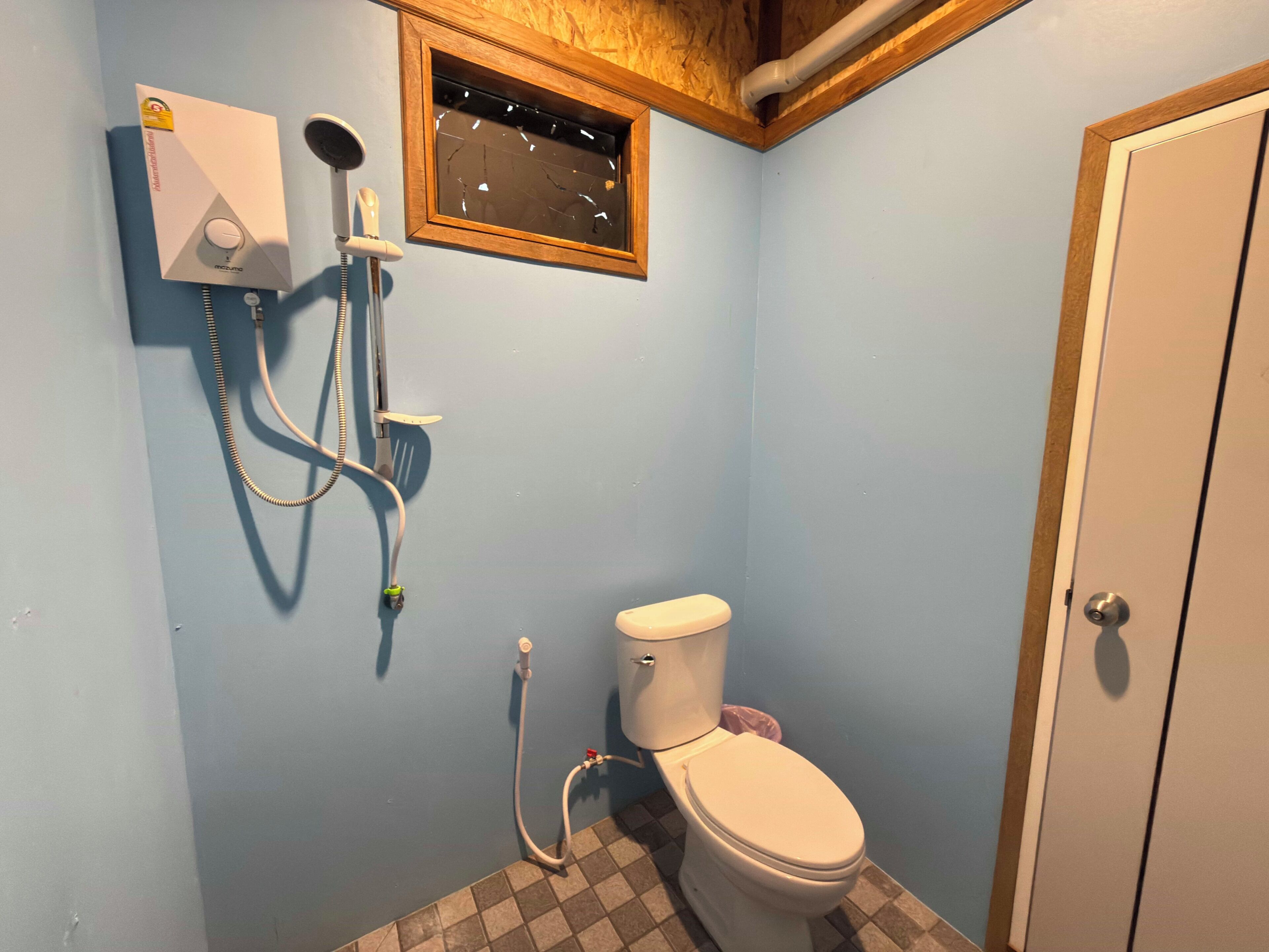 A bathroom with a toilet, a shower unit, and a wall-mounted heater.