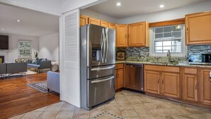 A modern kitchen with wooden cabinets, a stainless steel refrigerator, and a built-in microwave. - Cozy 4-BR Getaway :Private yard, Gazebo & Grill,  (Fairfax)