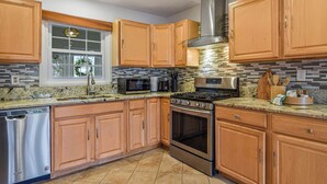 A modern kitchen with wooden cabinets, stainless steel appliances, and a tiled backsplash. - Cozy 4-BR Getaway :Private yard, Gazebo & Grill,  (Fairfax)