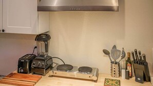 Ett kök med en brödrost, en mixer, två induktionshällar och ett knivställ.