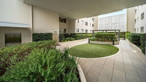 Un bâtiment moderne doté d’un espace extérieur abrité comprenant un jardin circulaire, un coin salon et un escalier.
