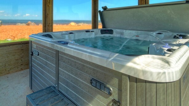 Ein Whirlpool mit Holzboden und großen Fenstern mit Blick auf eine Wüstenlandschaft.
