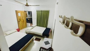 A small, clean room with two beds, a chair, a desk, a ceiling fan, and a window with curtains. - Sea Probal Beach Resort Saint Martin (Saint Martin's Island)