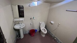 Casa de banho pequena e simples, com lavatório, sanita e espelho.